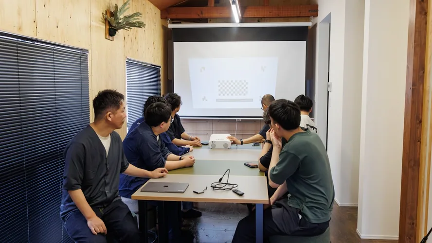 スクリーンを囲んで勉強会をしているダイニングテーブル