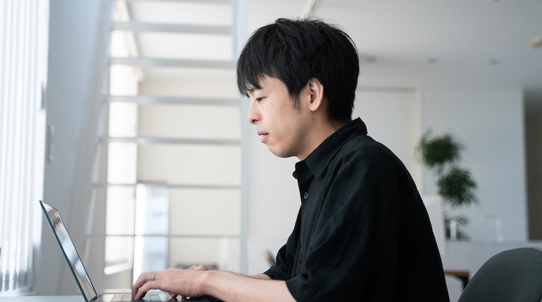 ひとりでノートパソコンに向かうプログラマの横顔