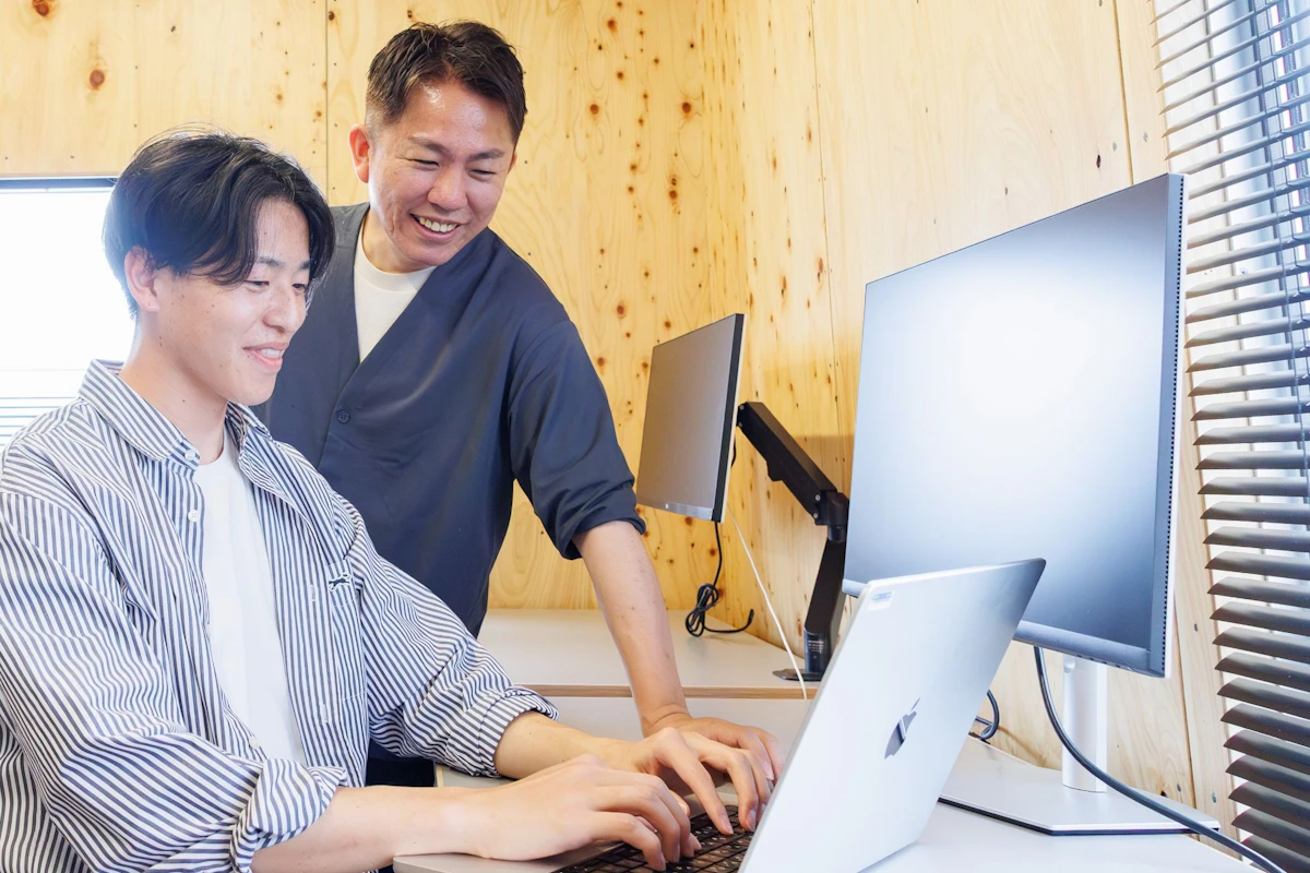 若手の画面を覗き込む先輩プログラマ